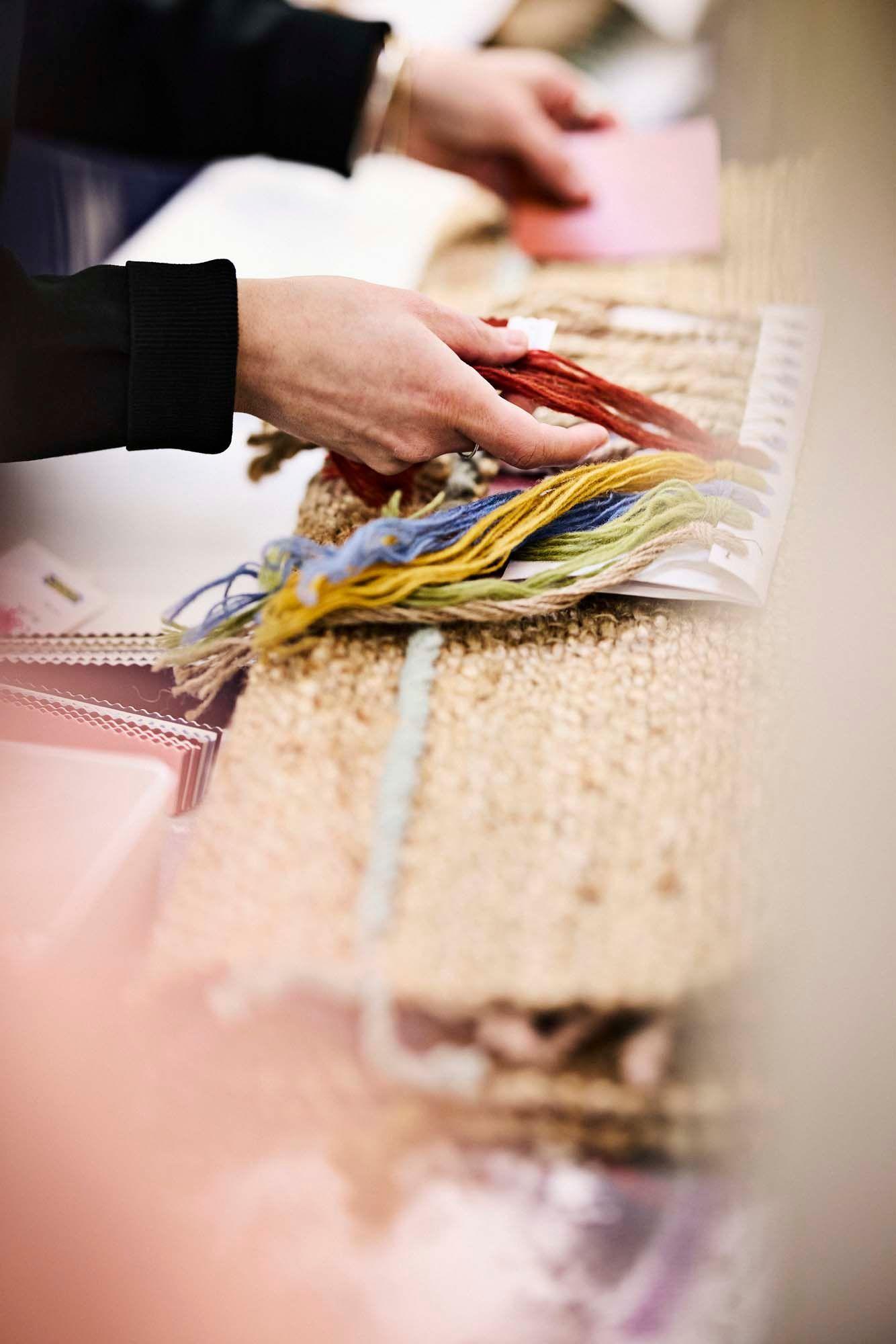A close-up of Paulin Machado handling colourful wool samples for the RAKLEV rug.