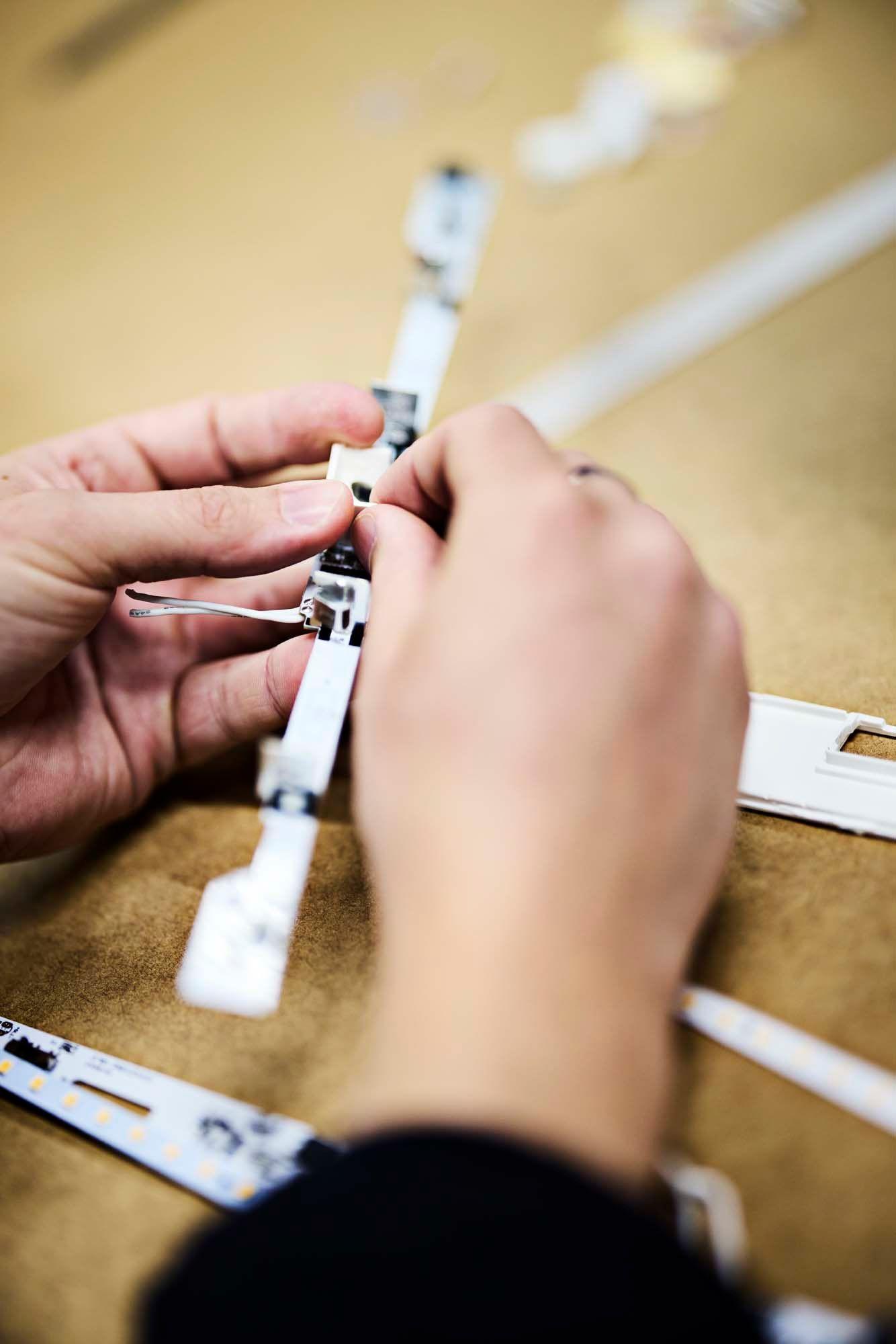 A pair of hands work with a lighting component.