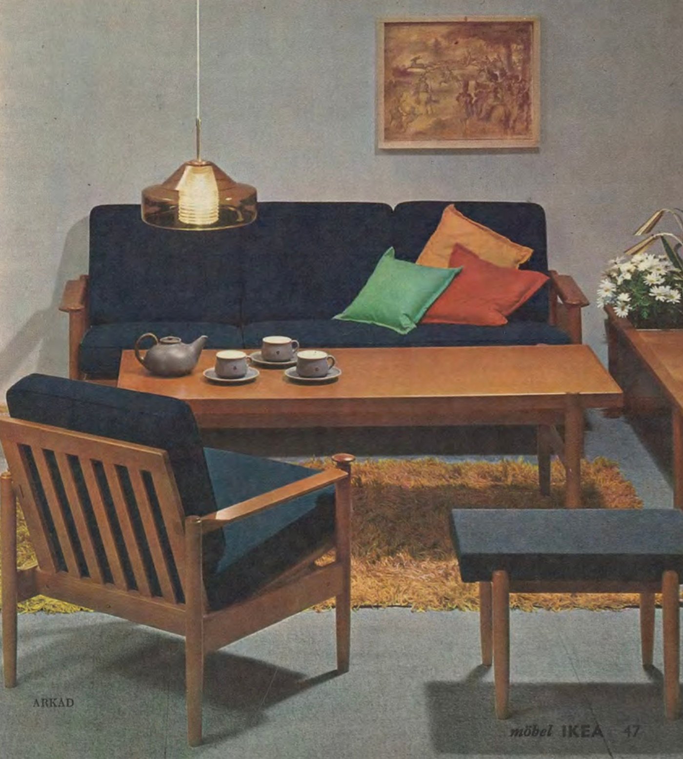 A living room from 1965 with a chair, sofa and footstool around a coffee table, with a yellow shag pile rug underneath.