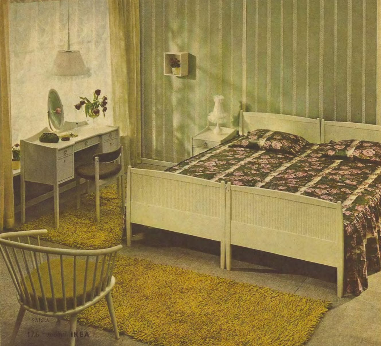 A green bedroom room set from 1965 featuring two single beds pushed together styled with green floral linen, green striped walls and a large green rug. 