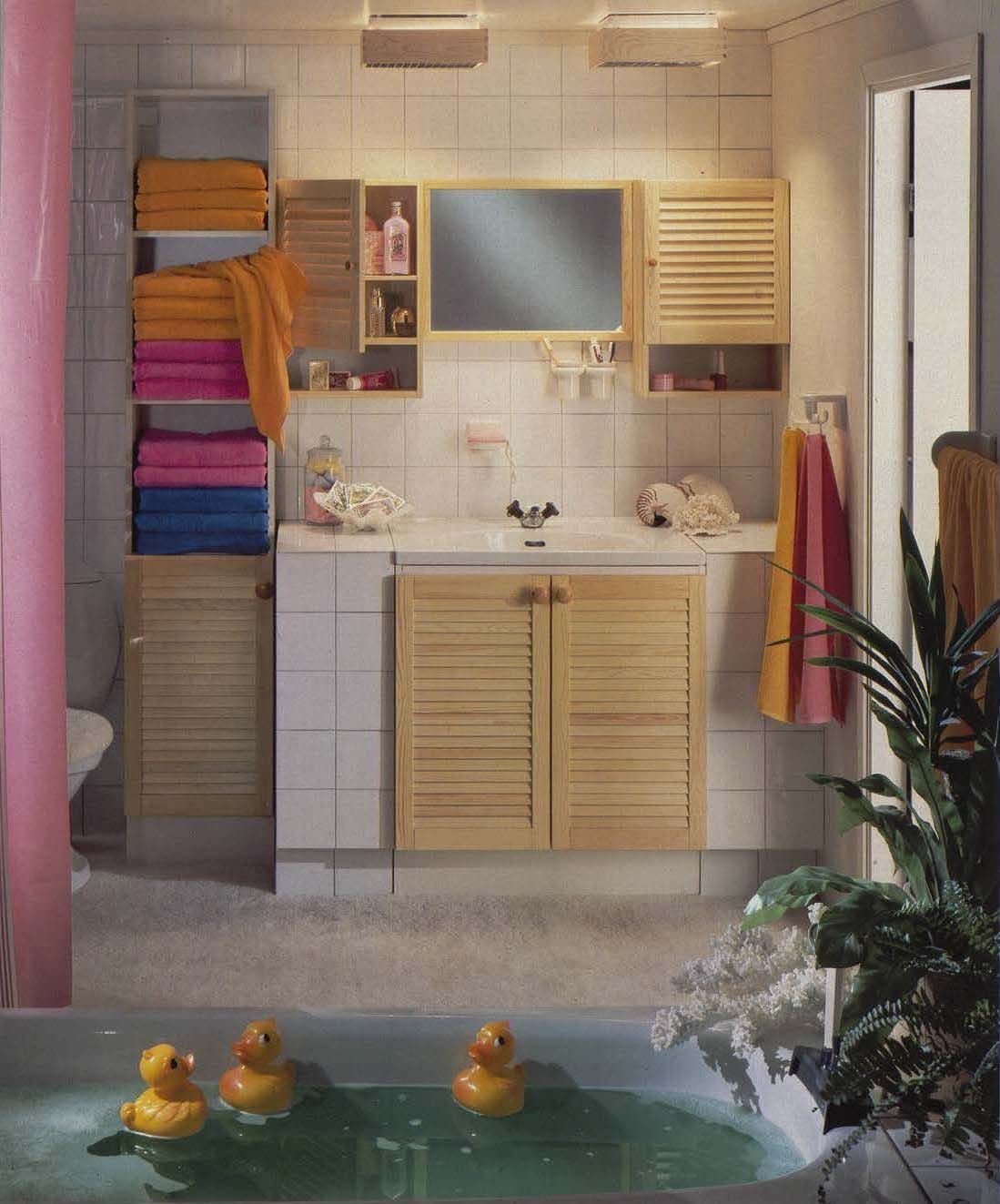 A white bathroom with pine cupboard fronts. In the foreground is a bathtub with three ducks.