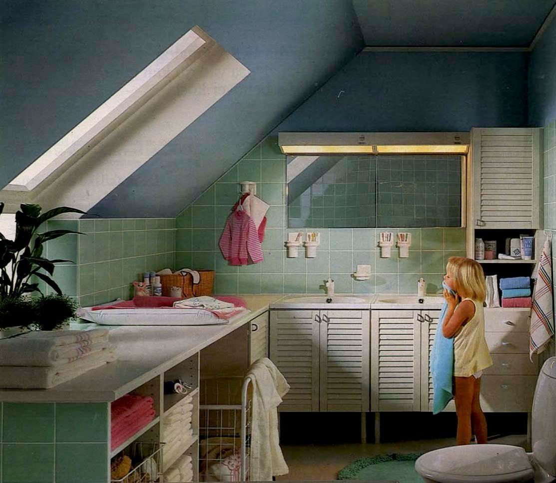 A green tiled bathroom with a sloped ceiling. There is plenty of storage.