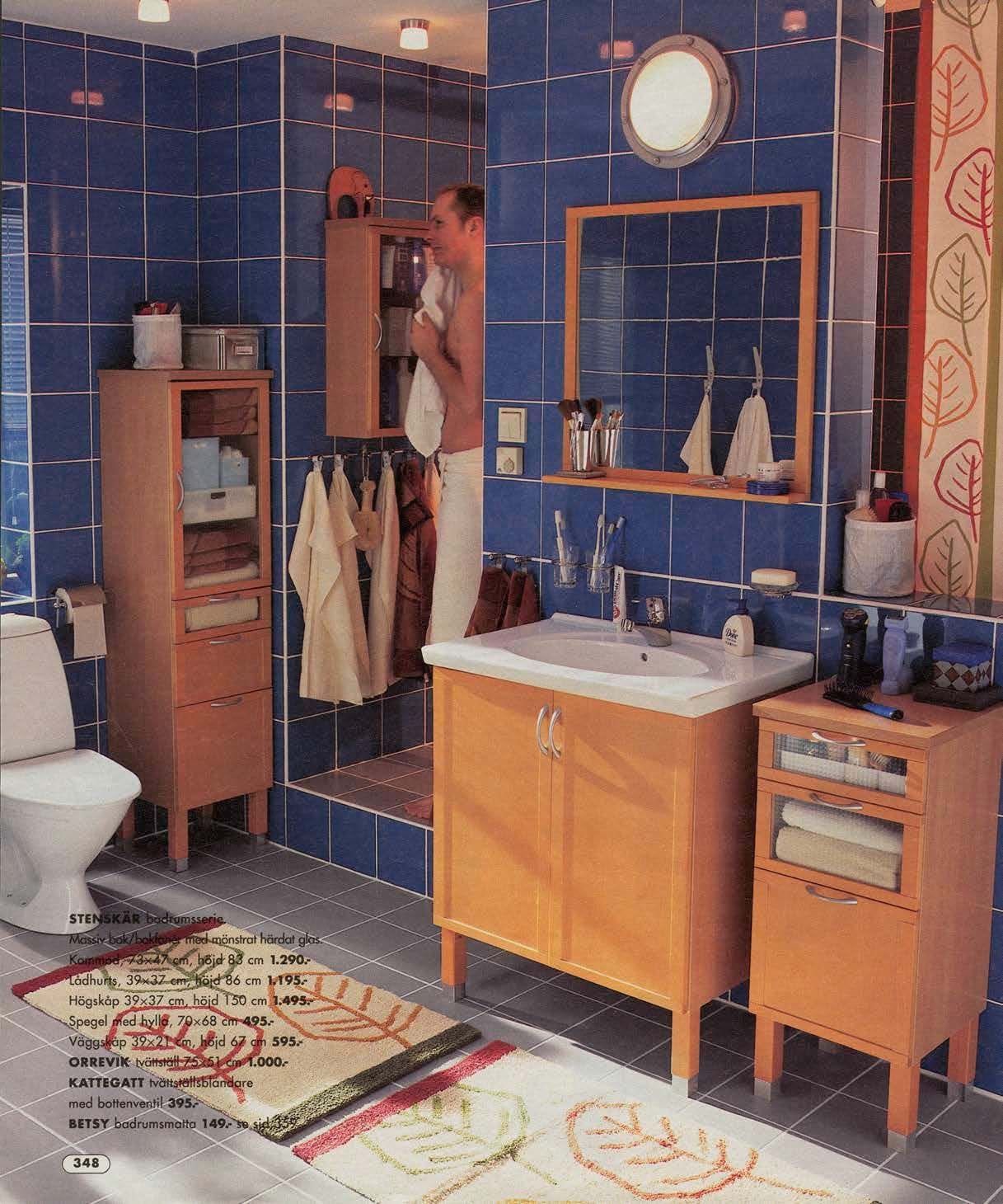 A blue tiled bathroom featuring wood bathroom furniture.
