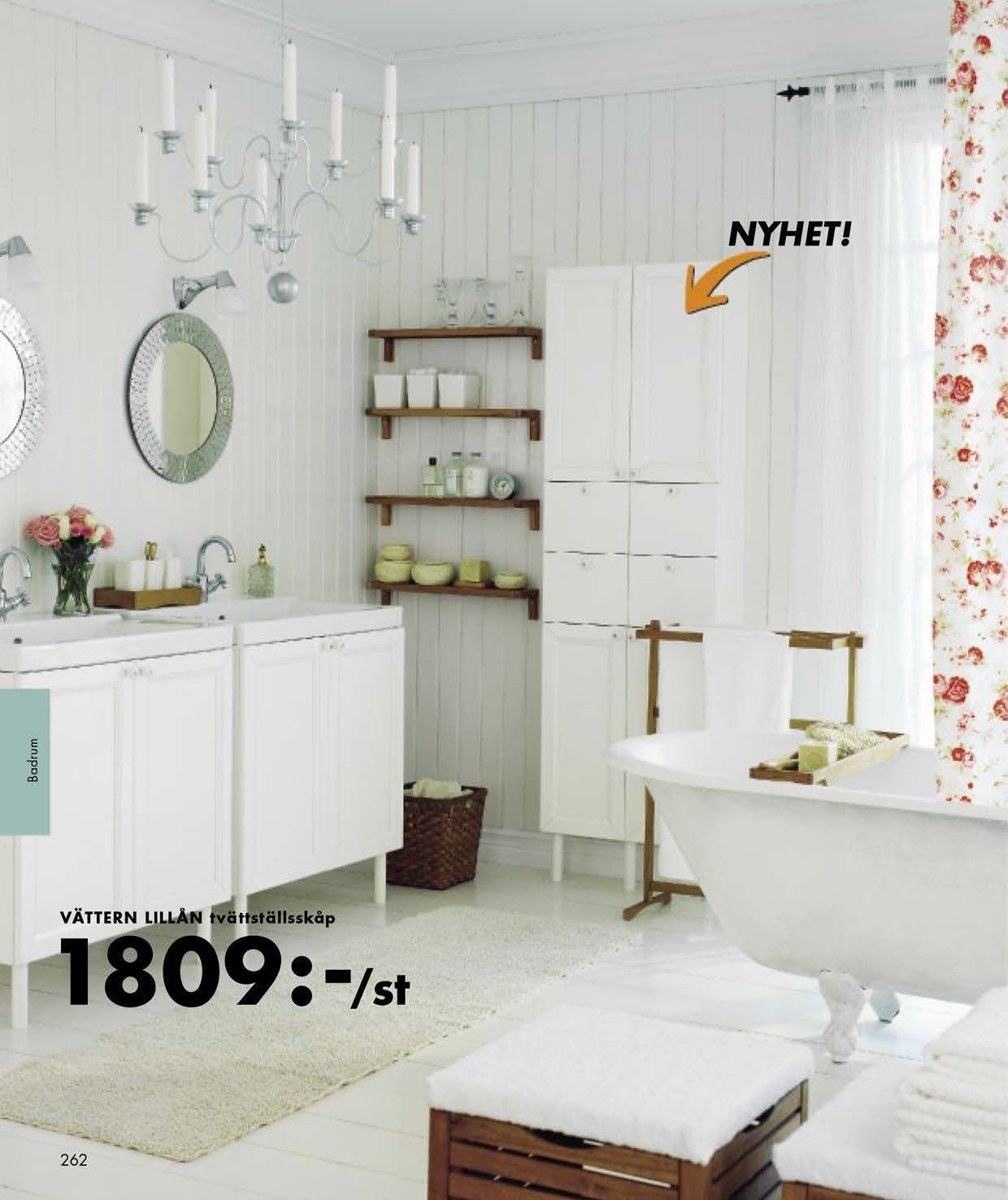 A white bathroom with a chandelier, a white bathtub and white furniture.
