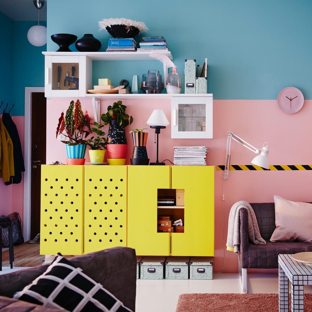 A wooden cupboard customised in yellow, against a blue and pink wall in a living room.