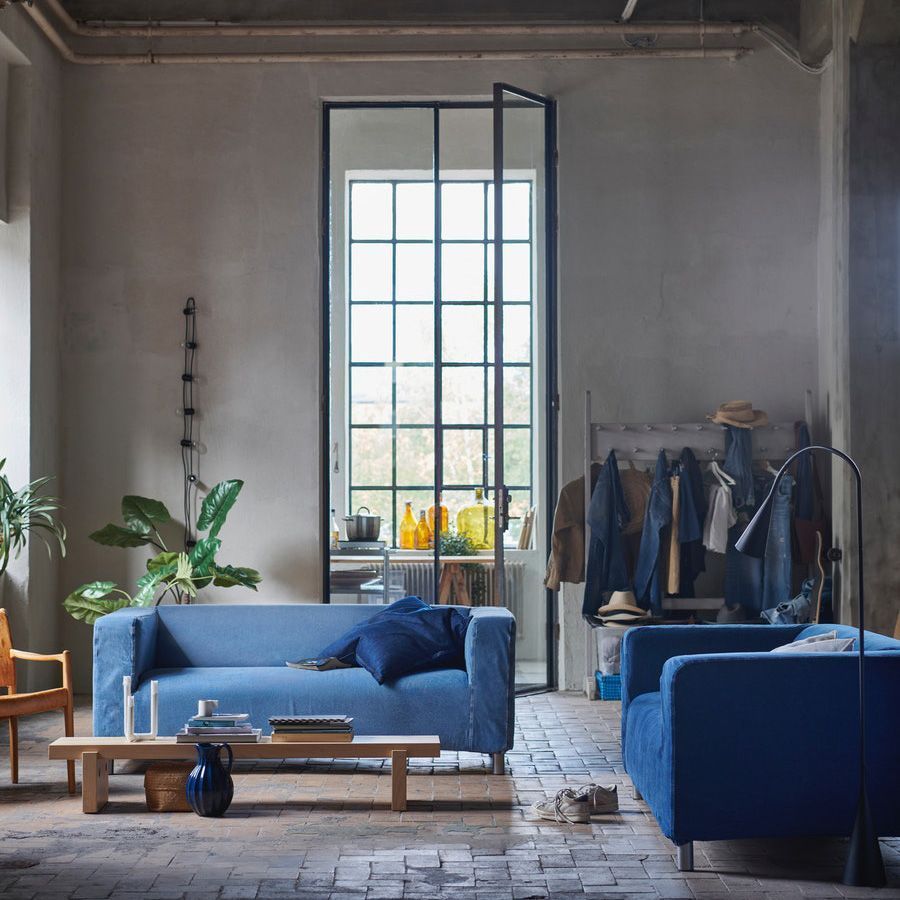 Two KLIPPAN sofas with denim covers in a large industrial space with double volume windows and ceilings.. 