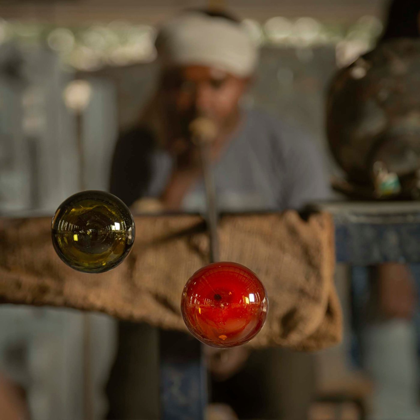 A person blows glass through a pipe.
