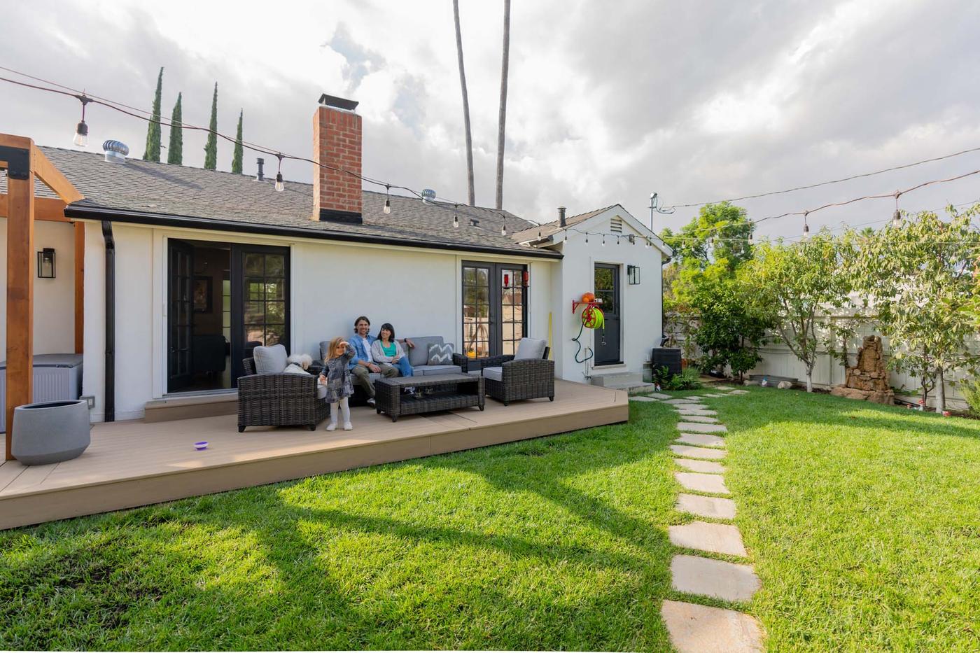 A family of three sitting on a terrace in front of a white house in Los Angeles.