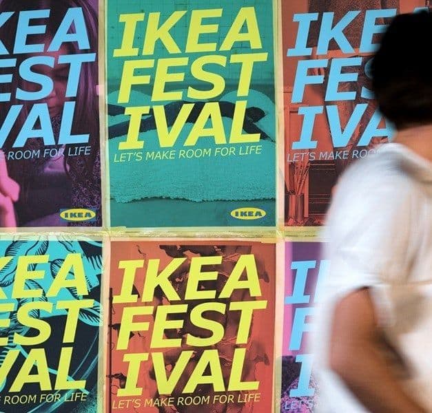 A person walking in front of a wall covered in posters for the IKEA Festival.