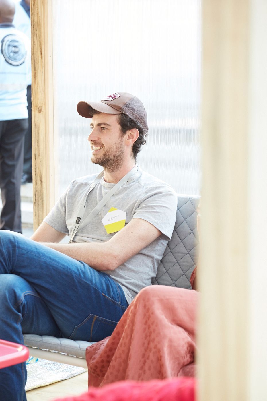 A man in a cap sits. He is smiling.