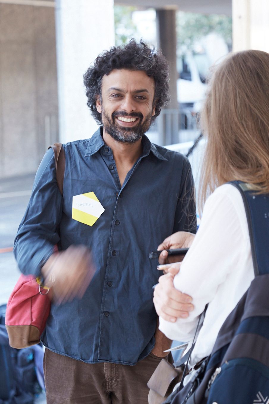 A man smiles. He is talking to a woman.