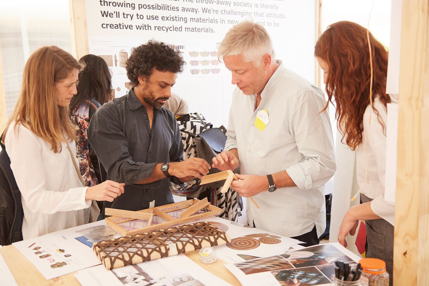 A group of people look at pieces of furniture construction.