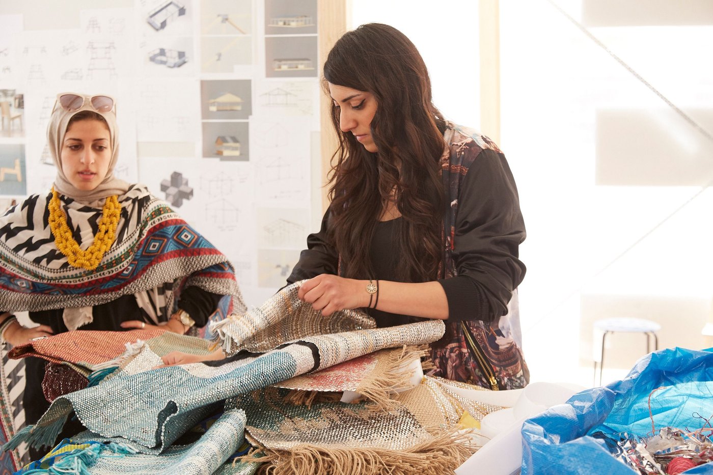 Two women look at woven fabrics.
