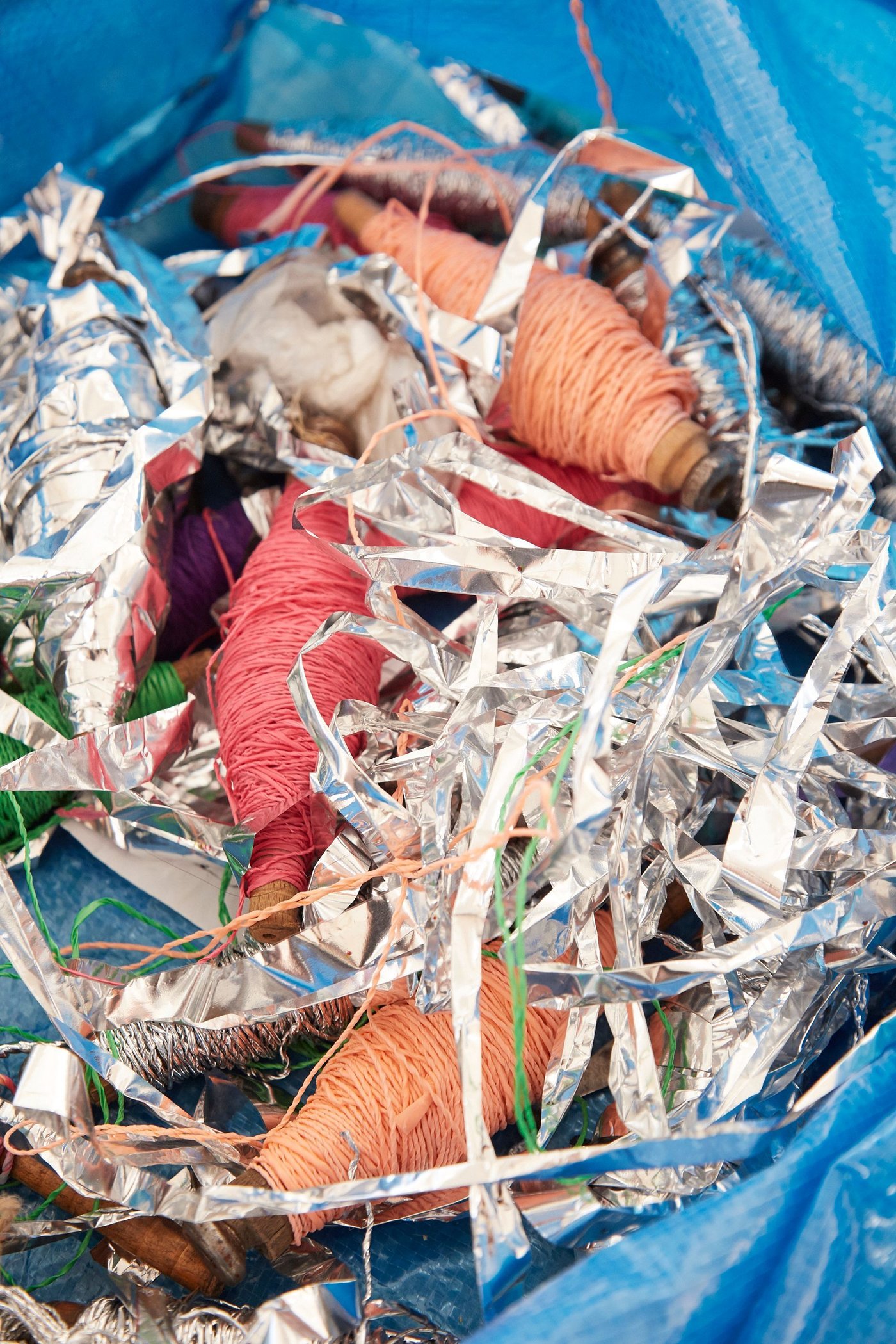 Spools of yarn and shredded plastic in a blue bag.