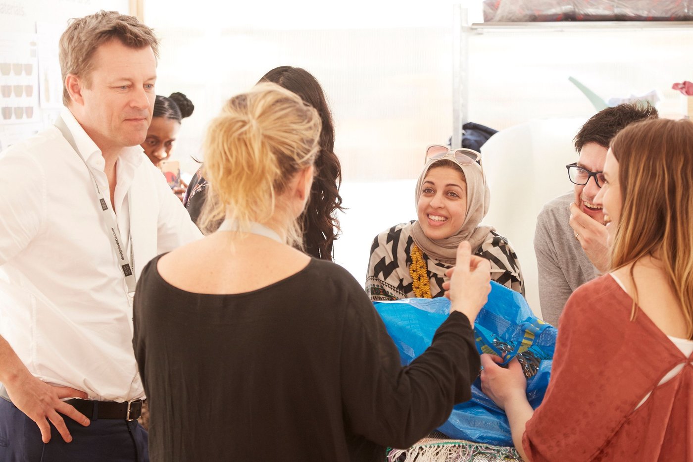 A man and some women look at a blue FRAKTA bag. They are talking.