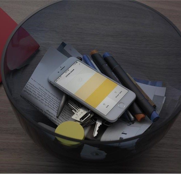 A telephone with a yellow screen in a bowl with keys, etc.
