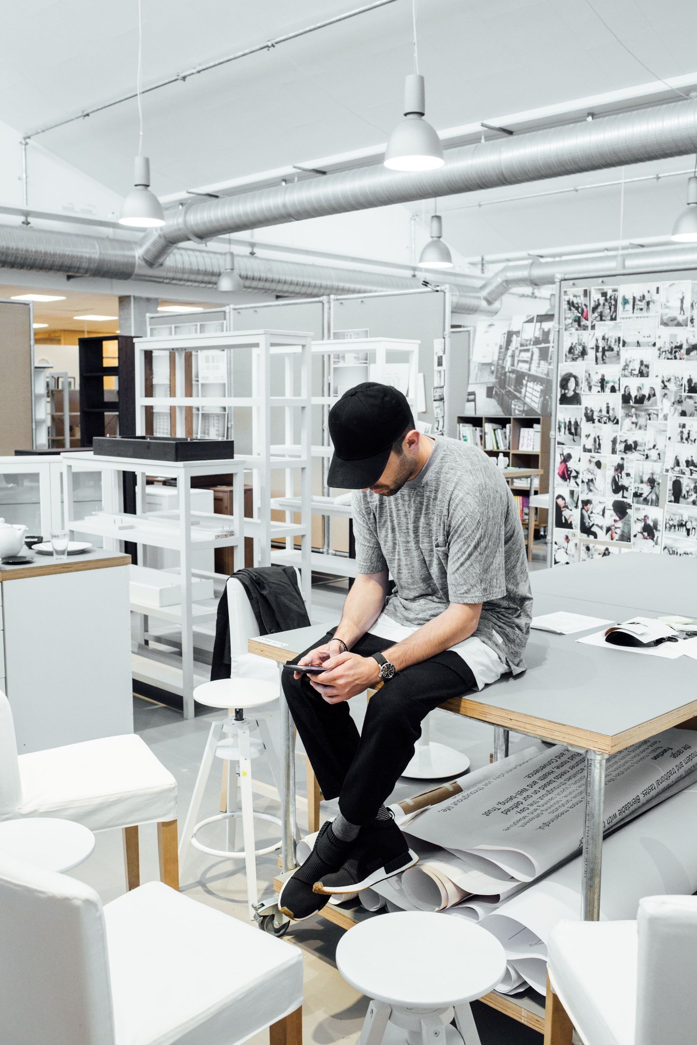A person sits on a table in a white, brightly-lit design studio.