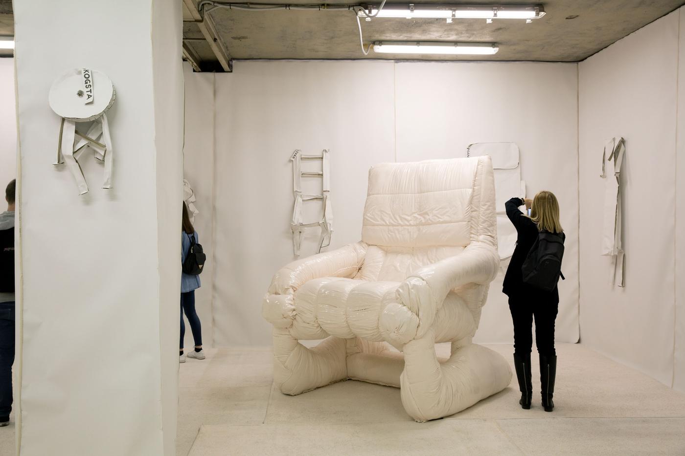 A display of a big white puffy chair. A person is taking a photo of the chair.