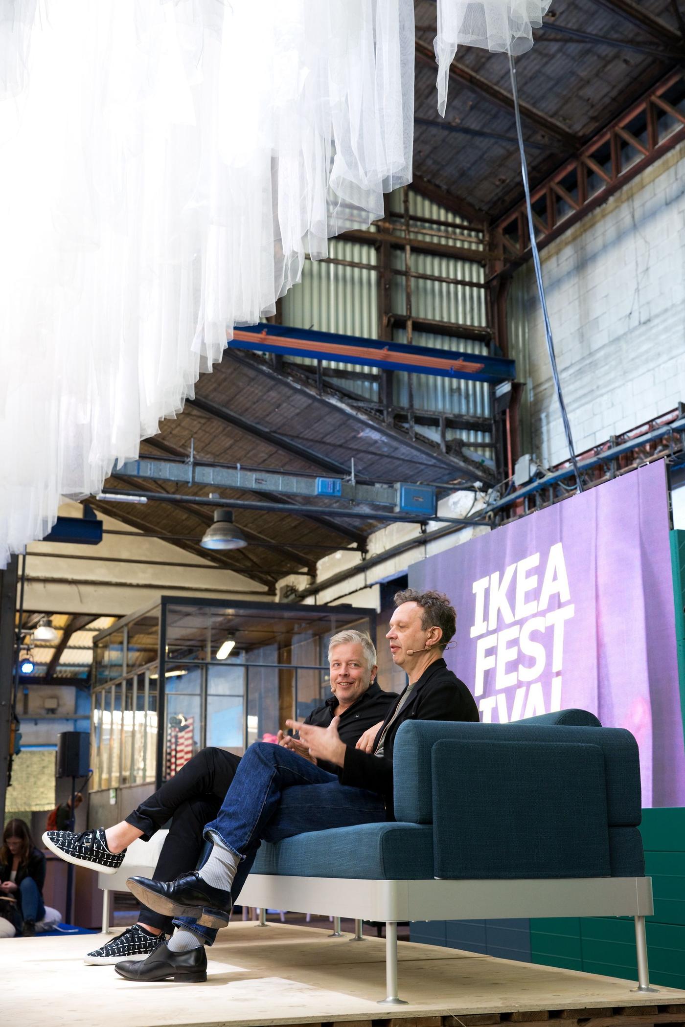 People seated on a sofa on a stage at an event.