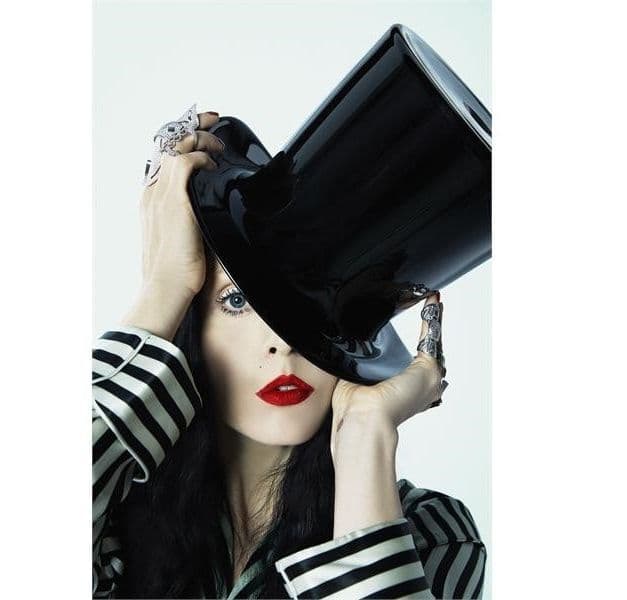 A woman wears a black top hat tipped over one eye.