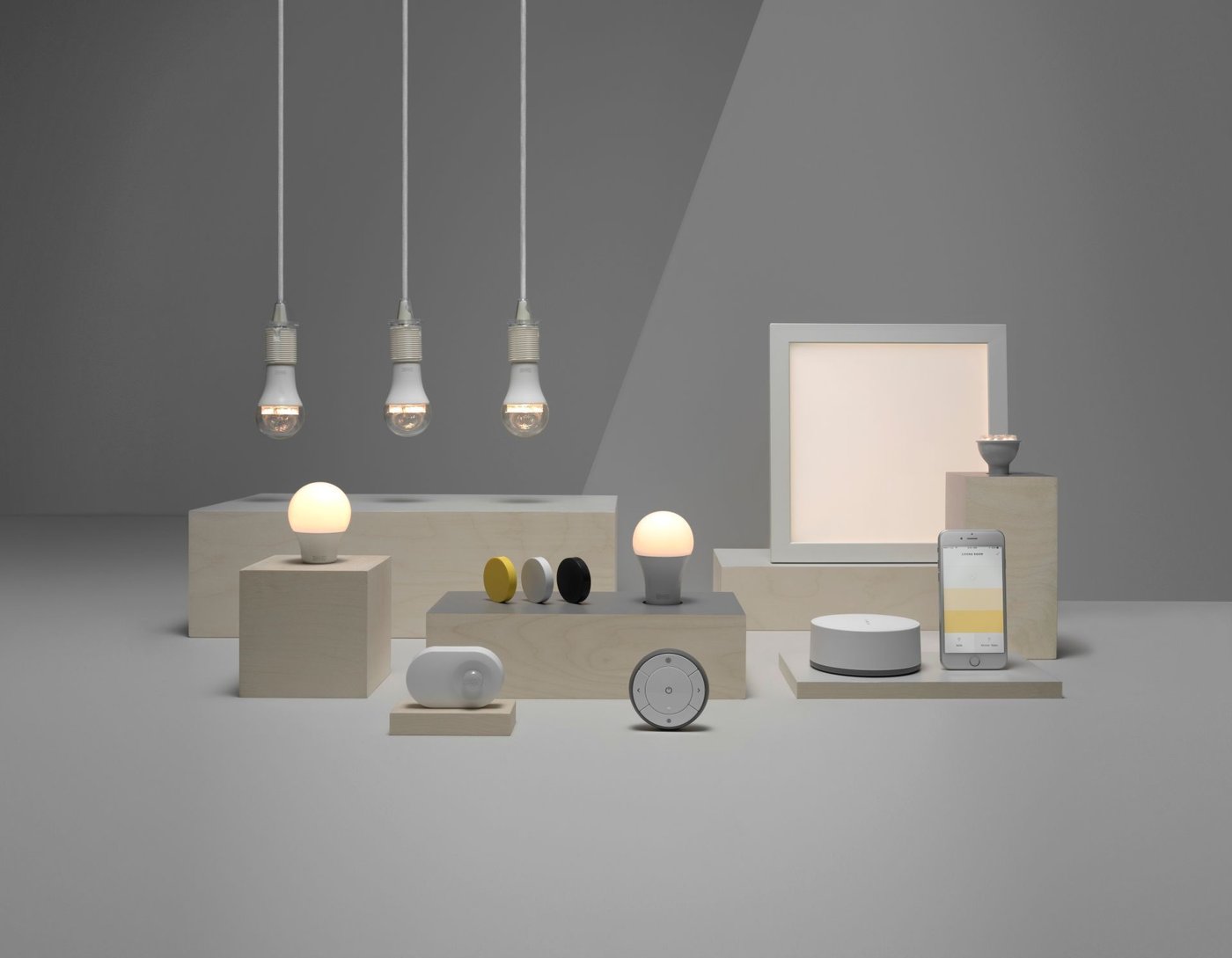 A range of smart operated products, including light bulbs, speakers and a phone against a grey background.