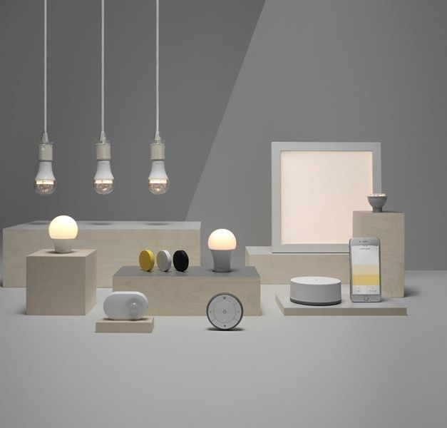A range of smart operated products, including light bulbs, speakers and a phone against a grey background.