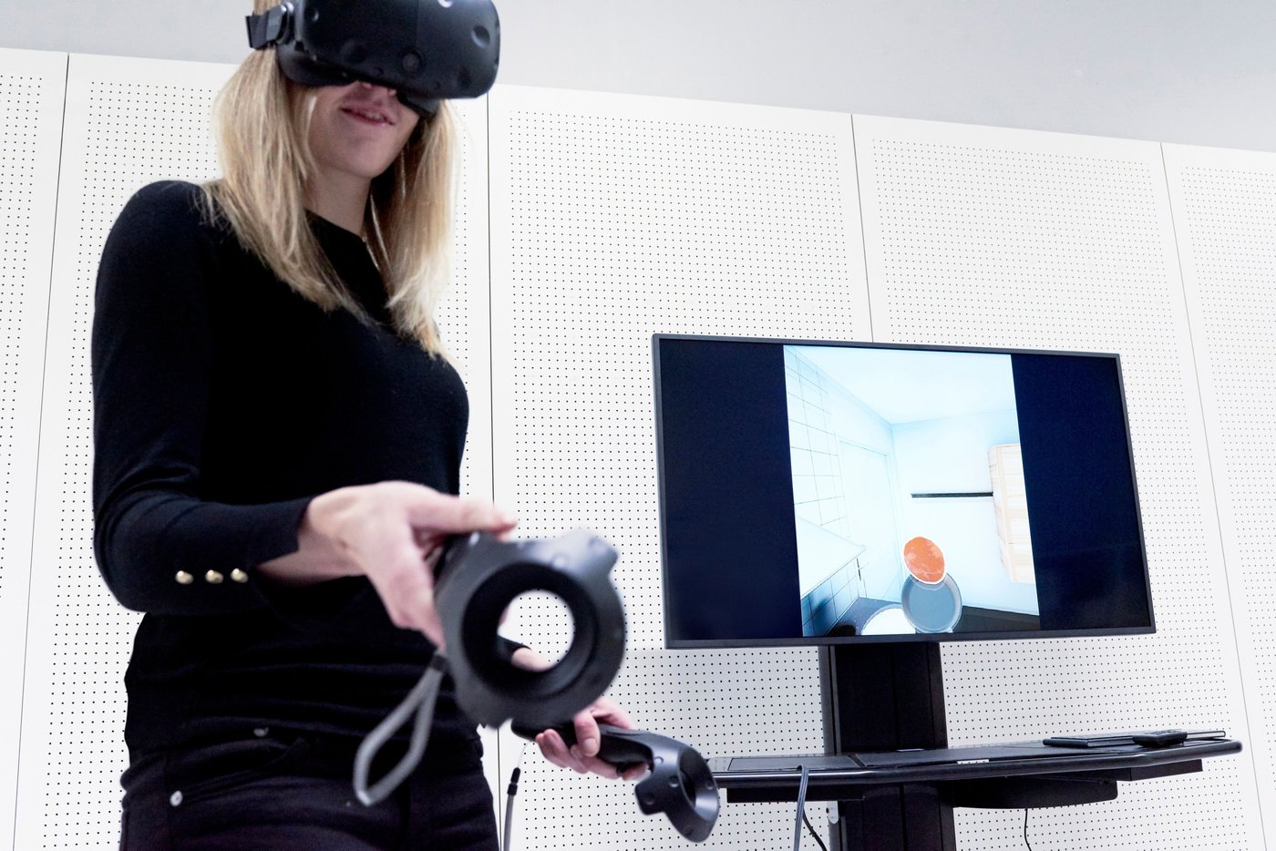 A woman is wearing virtual reality goggles. She is making a virtual pancake.