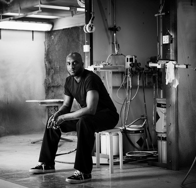Black and white photo of Virgil Abloh seated on a stool.
