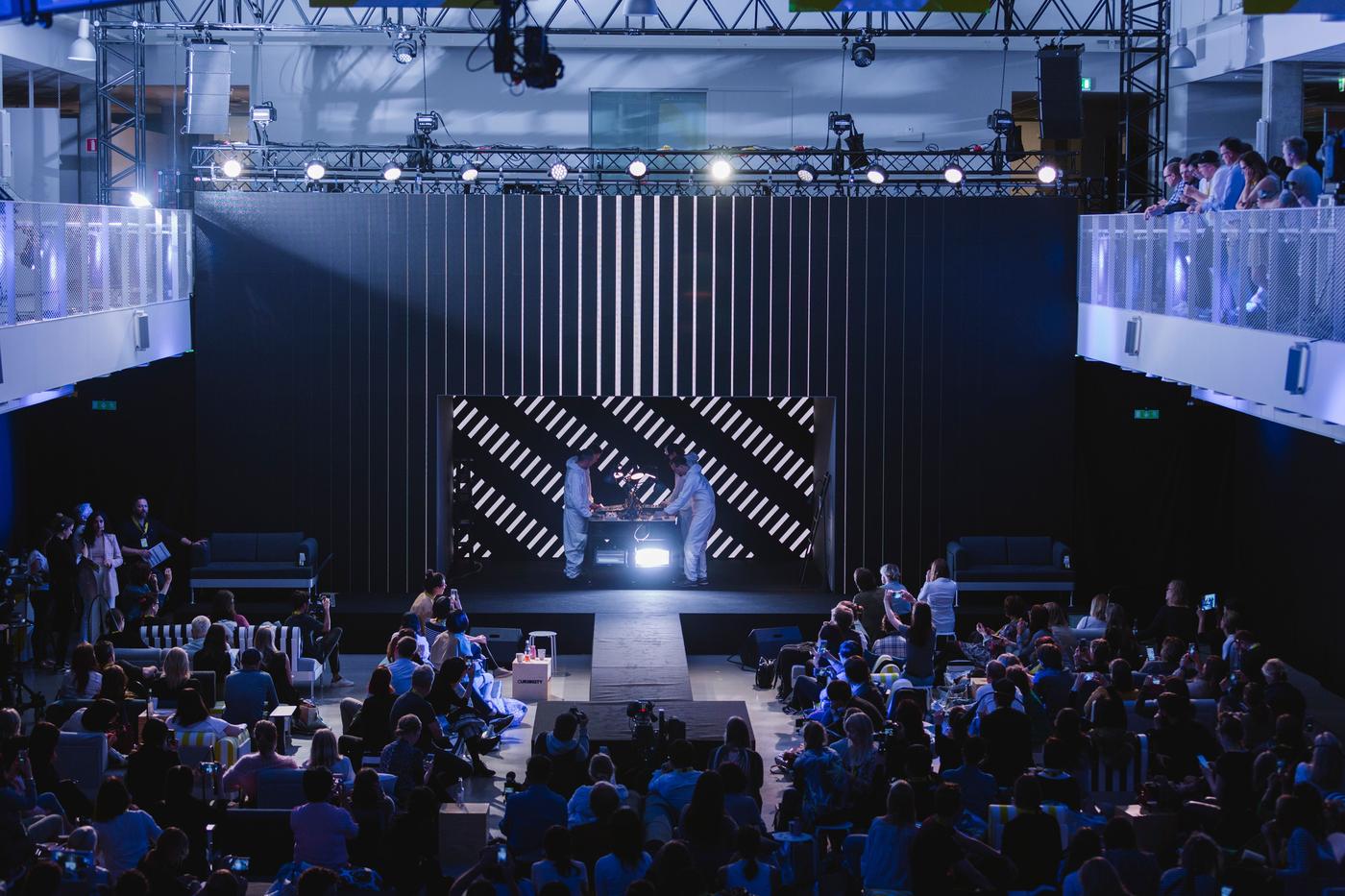 A large hall filled with people facing a stage.