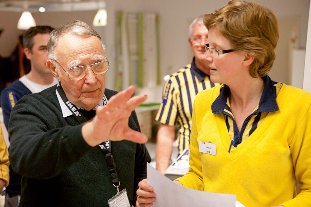 Ingvar Kamprad talks to an IKEA co-worker and gestures with his hand.
