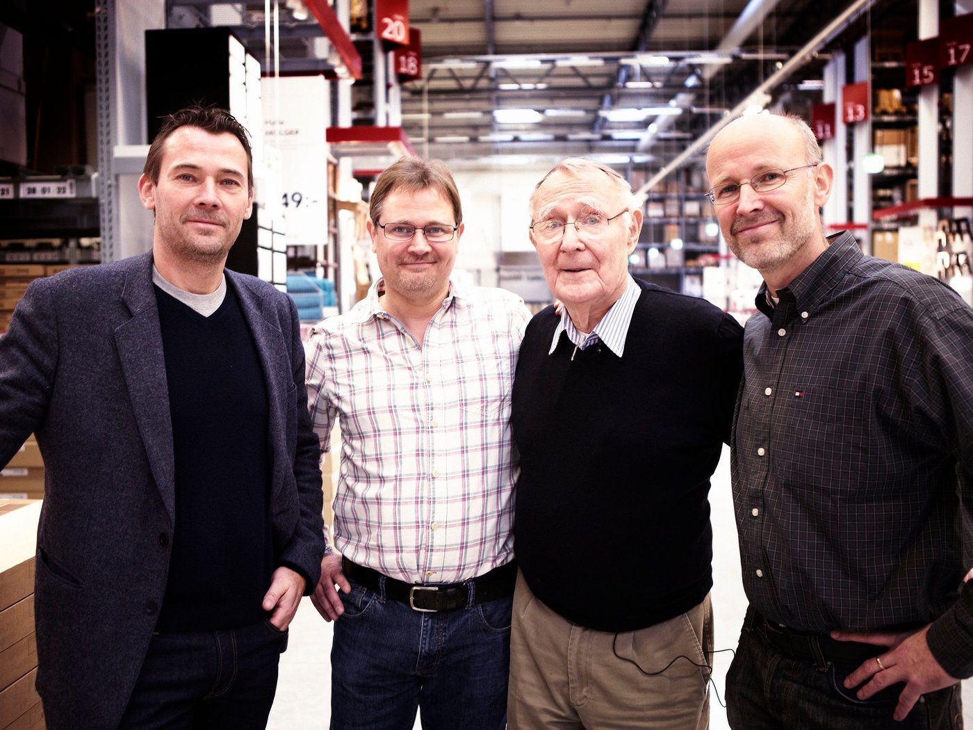 Ingvar Kamprad and his three sons standing side by side in a warehouse.