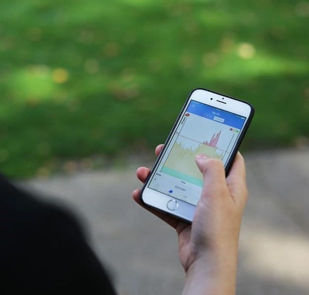 A hand holds a mobile phone outside.