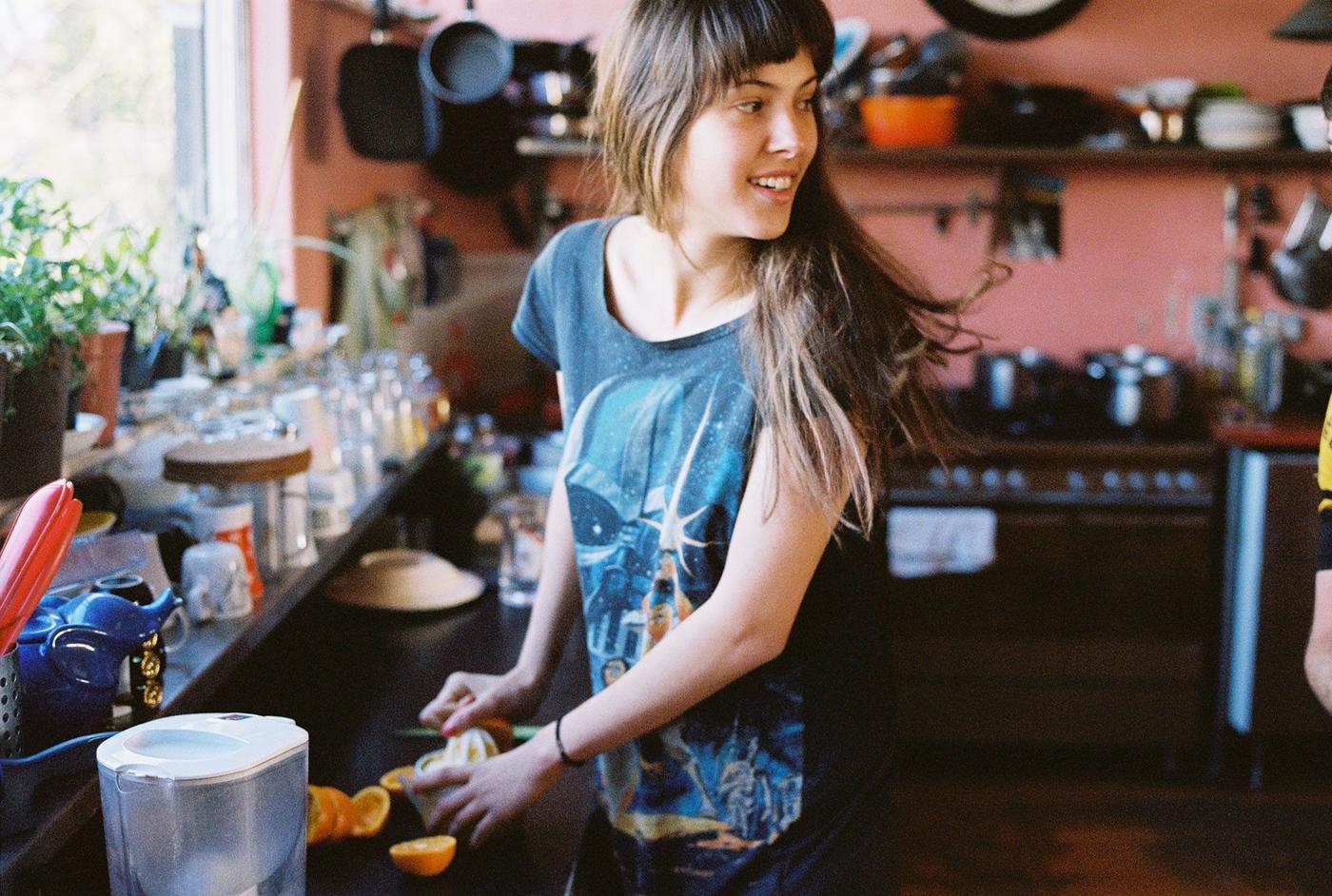 A woman talks to someone in the kitchen while she prepares food.