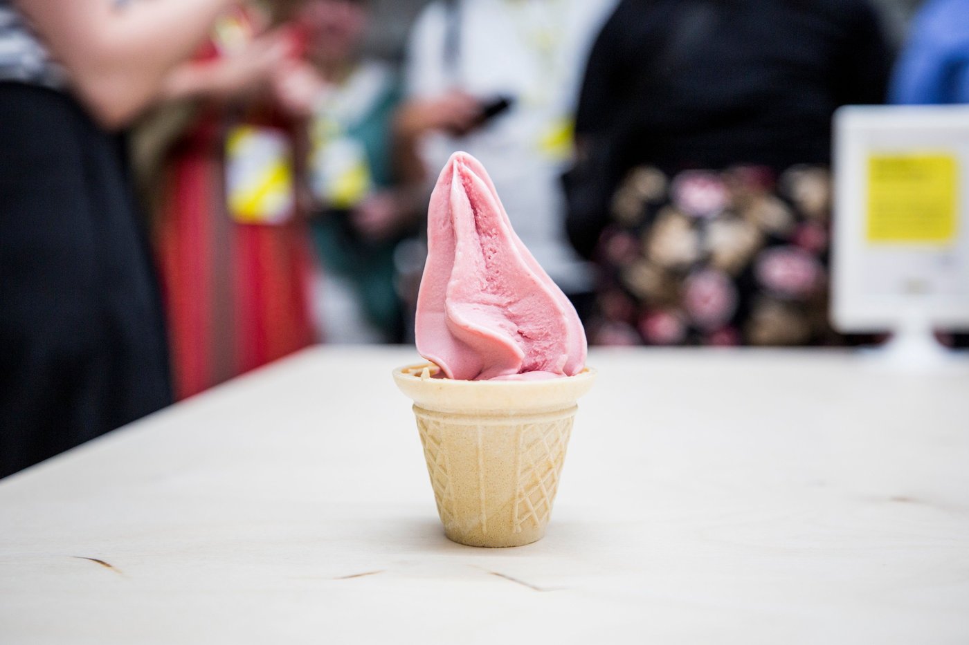 A cup of strawberry soft-serve ice cream on a white surface.
