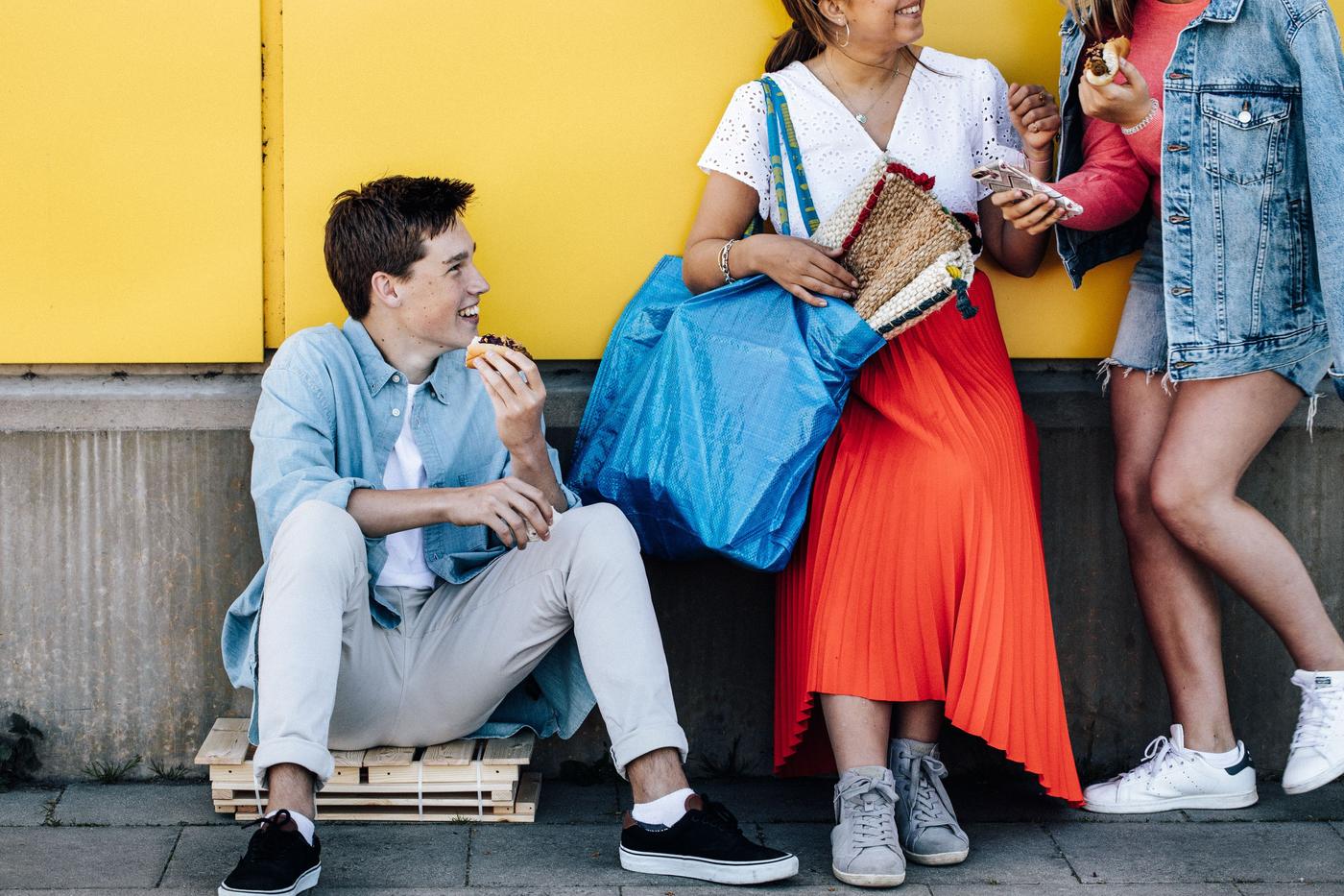 Three people enjoying the veggie hotdog in front of an IKEA store