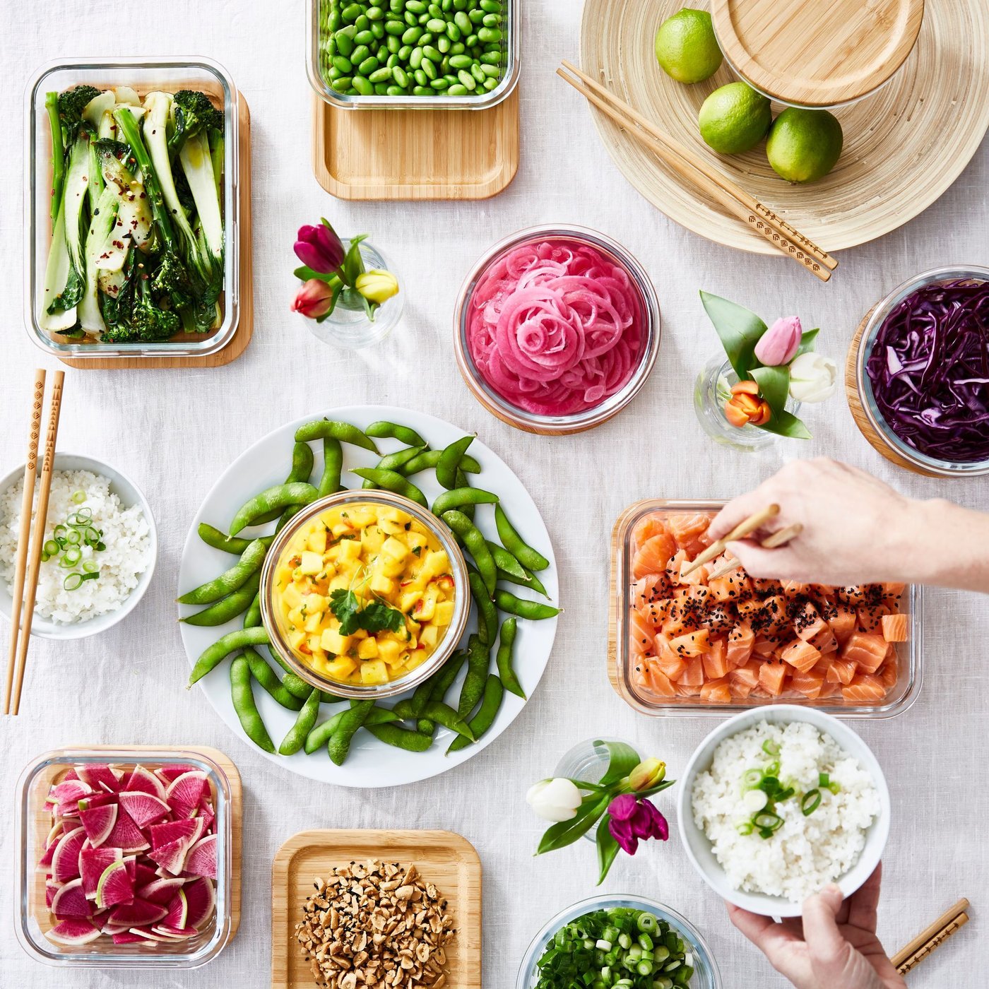 Overhead view of colourful prepped vegetables in different food containers on a white surface.