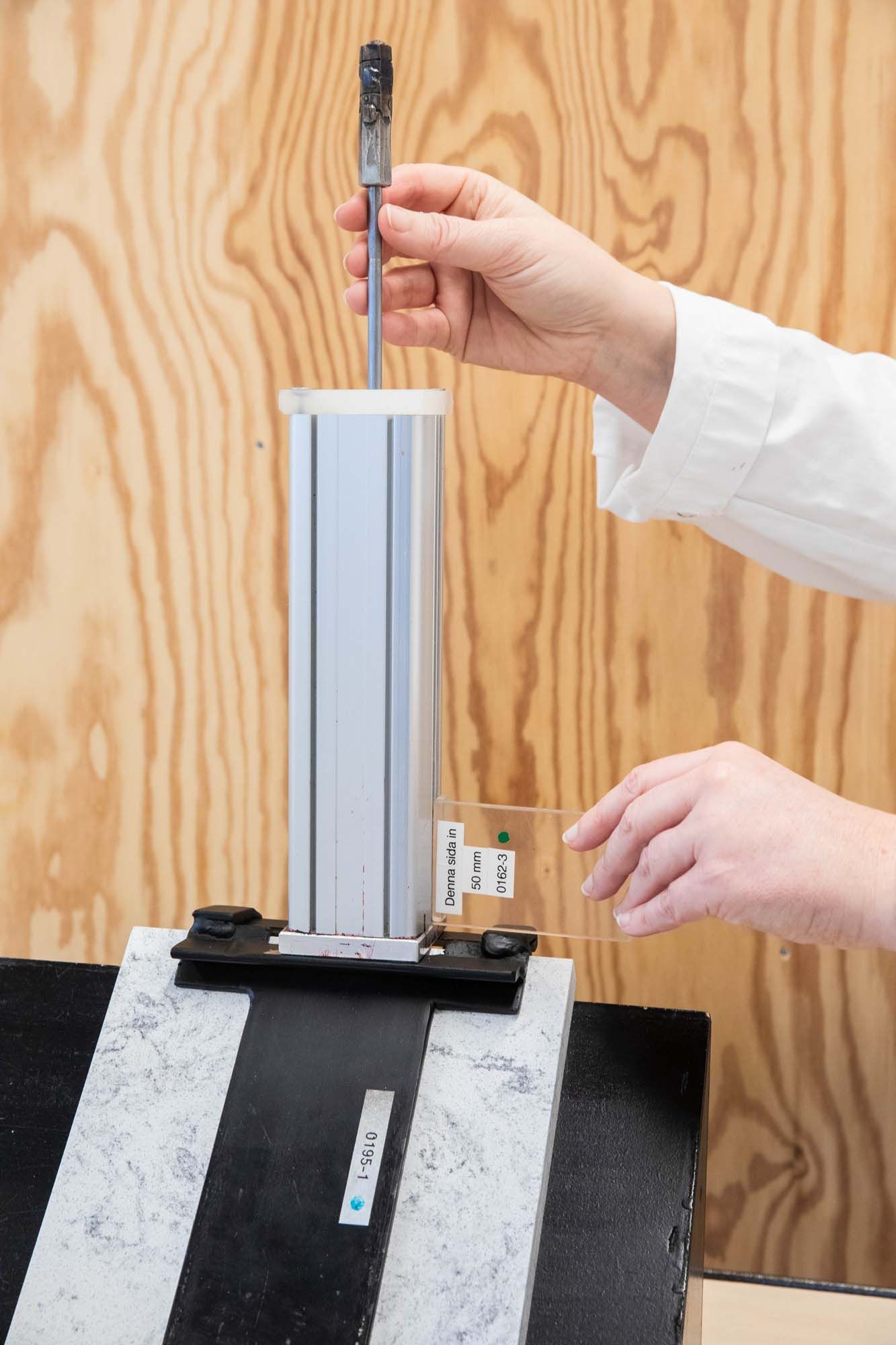 A person's hands preparing a piece of LOCKEBO worktop for an edge impact test.