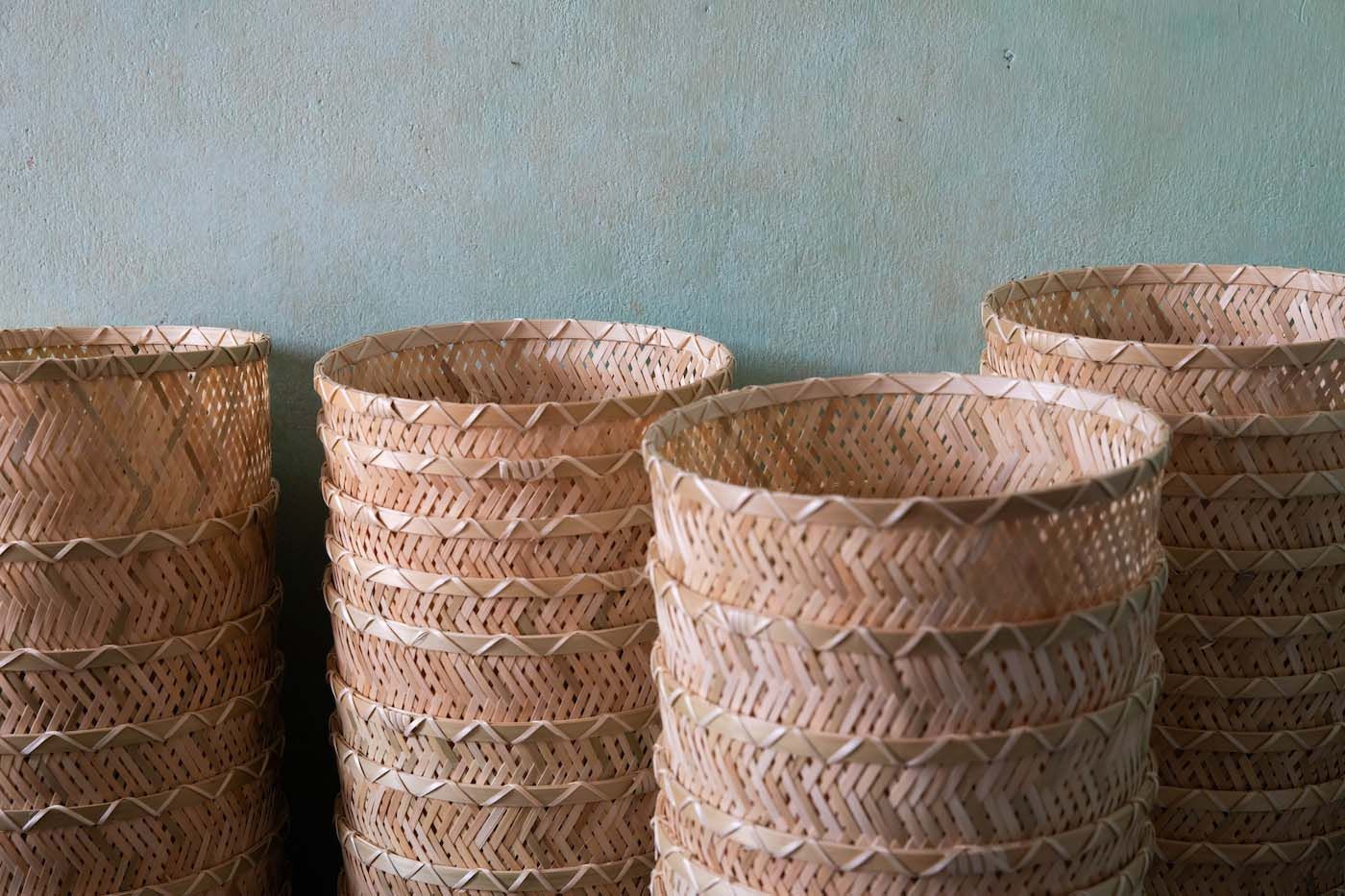 Four stacks of hand woven baskets against a light blue wall.