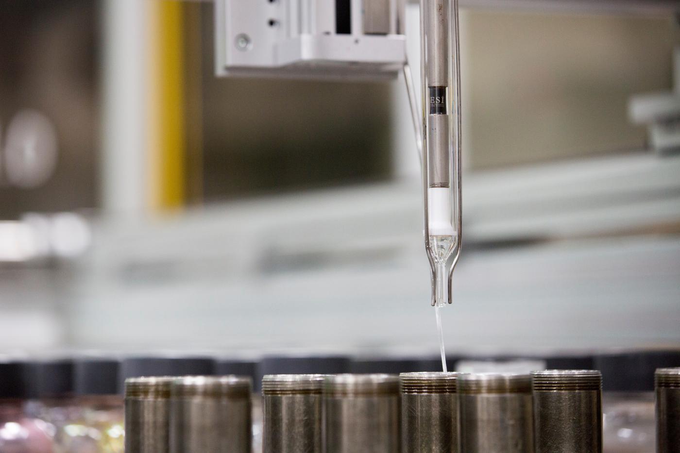 Mineral-based surface treatment drips down from a glass tube onto metal.