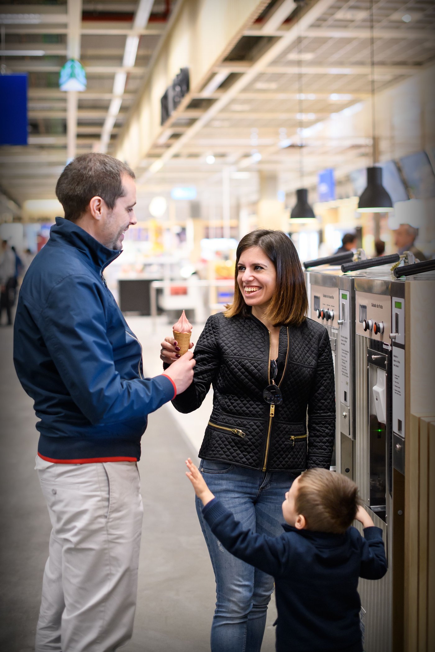 Two adults and a child standing together at an ice cream dispensing machine at an IKEA Bistro