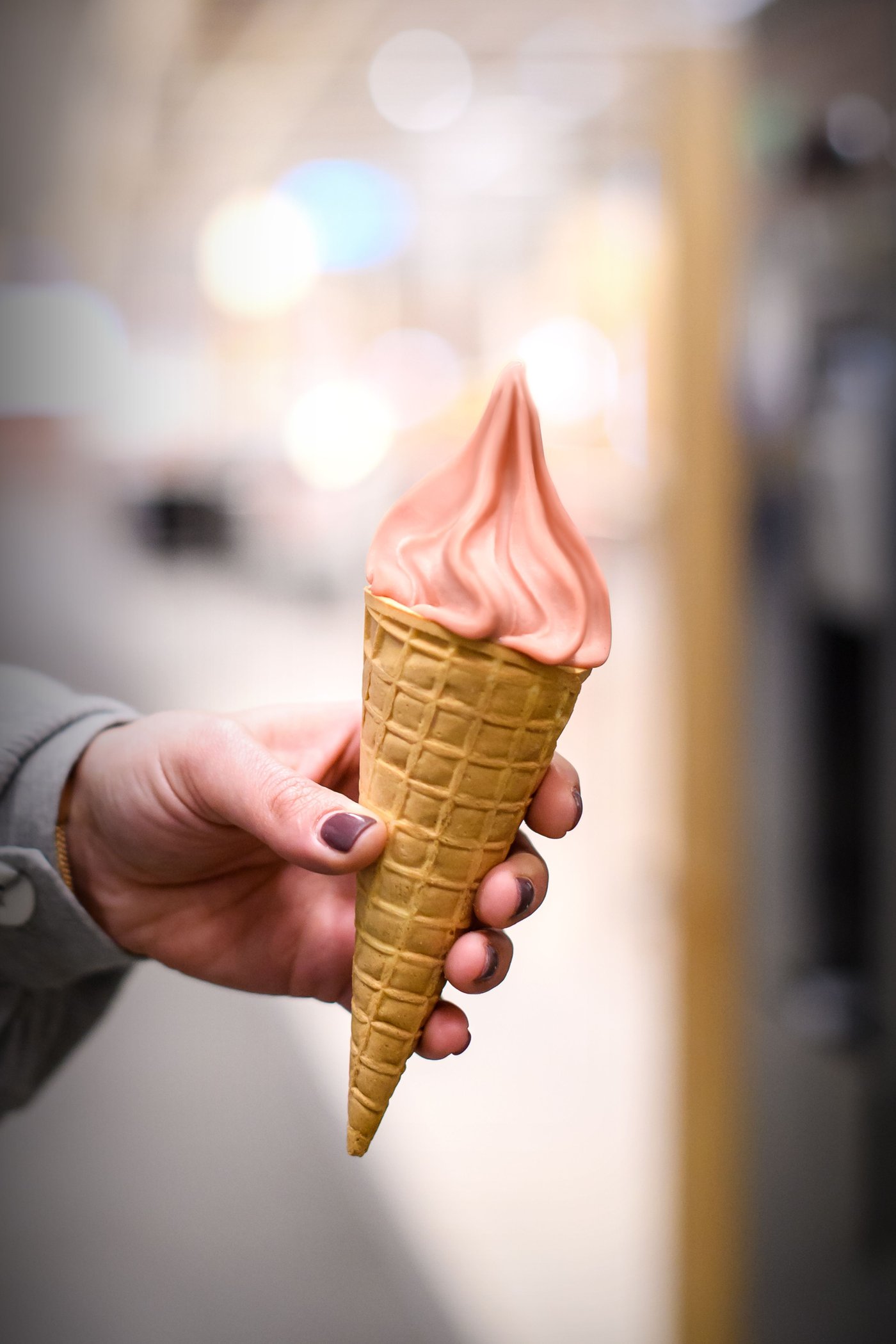 Hand holding a strawberry ice cream cone.