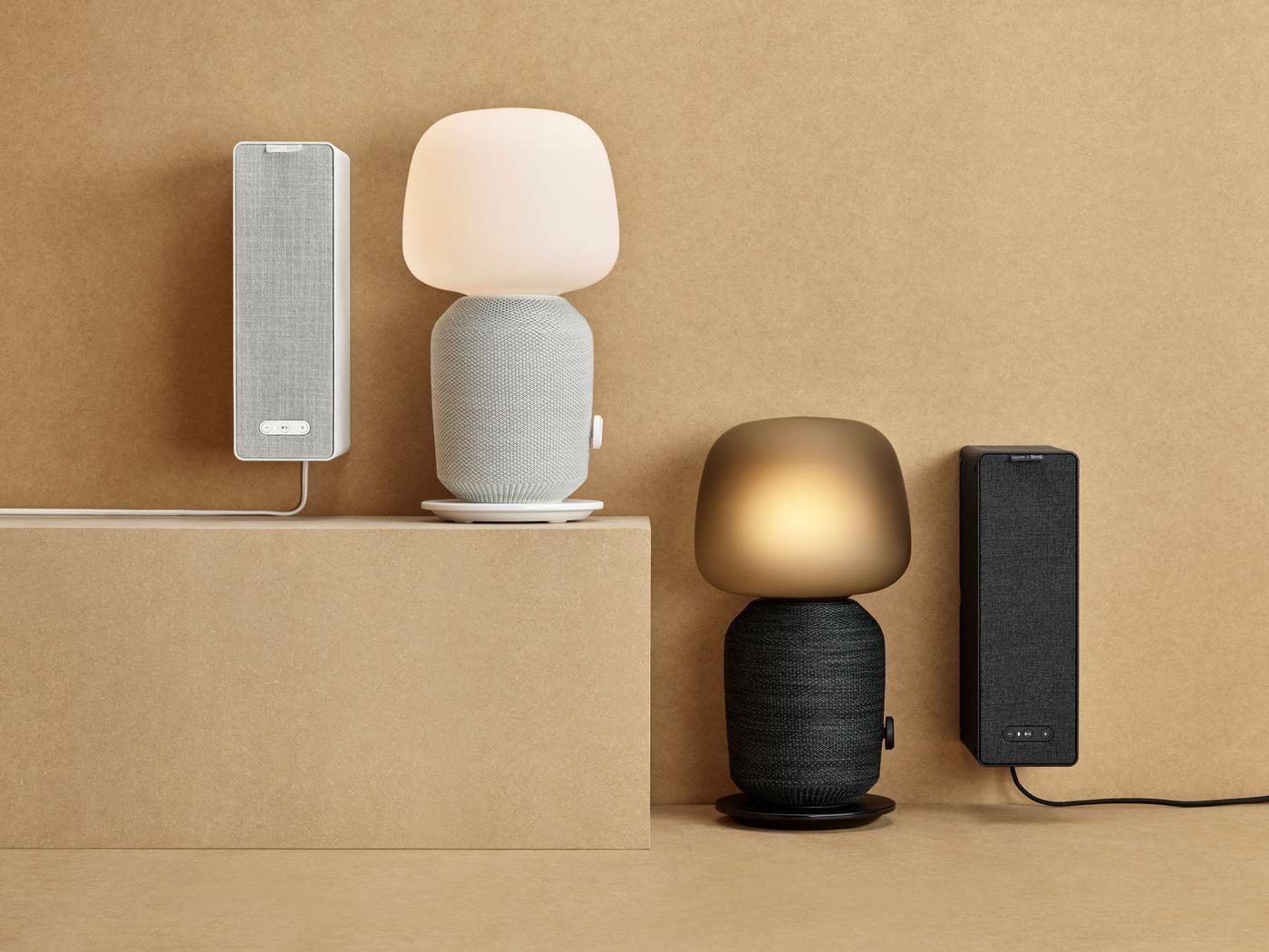 Two speaker lamps and two bookshelf speakers from the SYMFONISK series displayed on a warm sandy-coloured background.