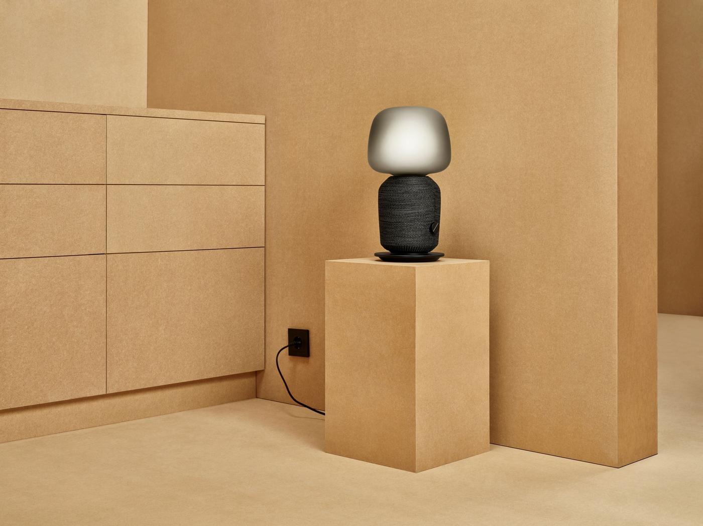 SYMFONISK WiFi speaker lamp displayed on a plinth in a warm sand-coloured roomset.