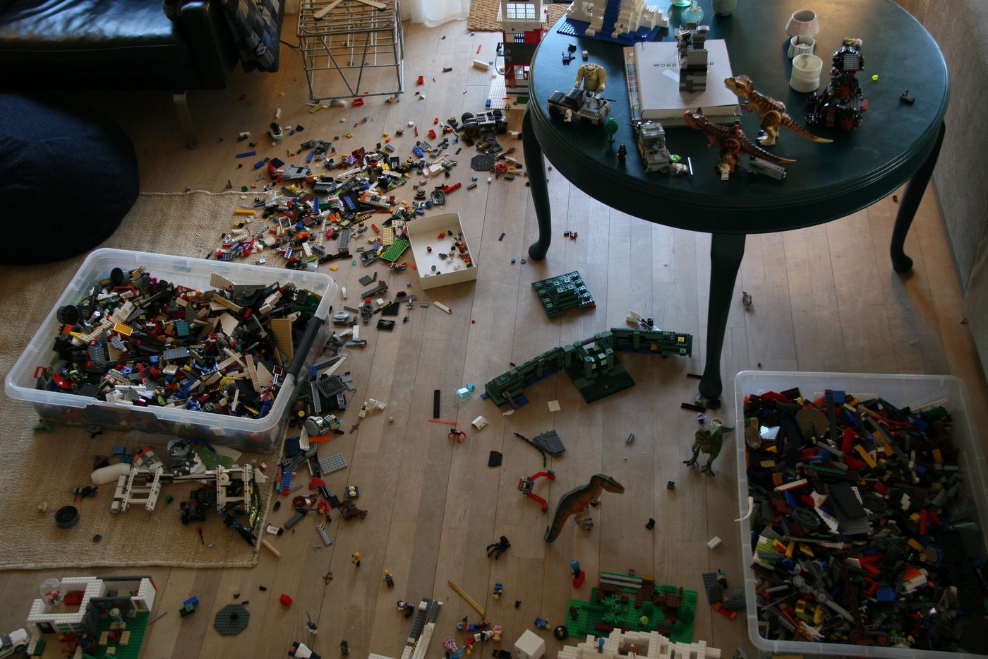 Lego pieces are scattered over the wooden floor of a home.