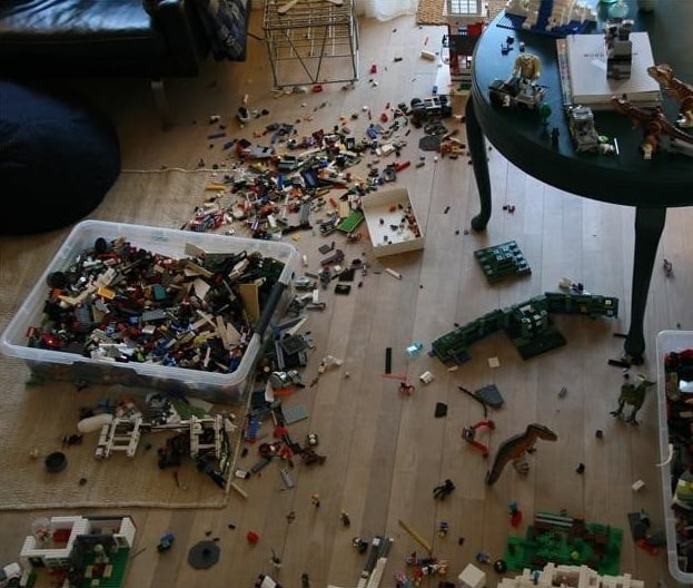 Lego pieces are scattered over the wooden floor of a home.