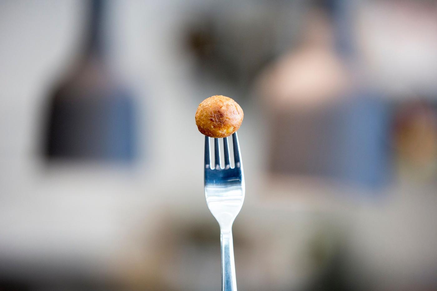 An upright fork holding up a plant-based protein ball.