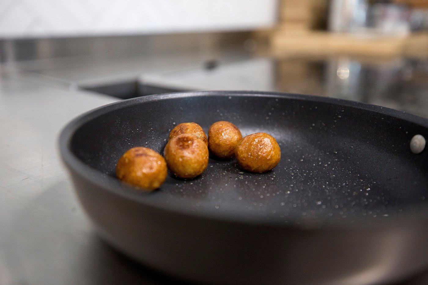 Meatballs cooking in a black pan.