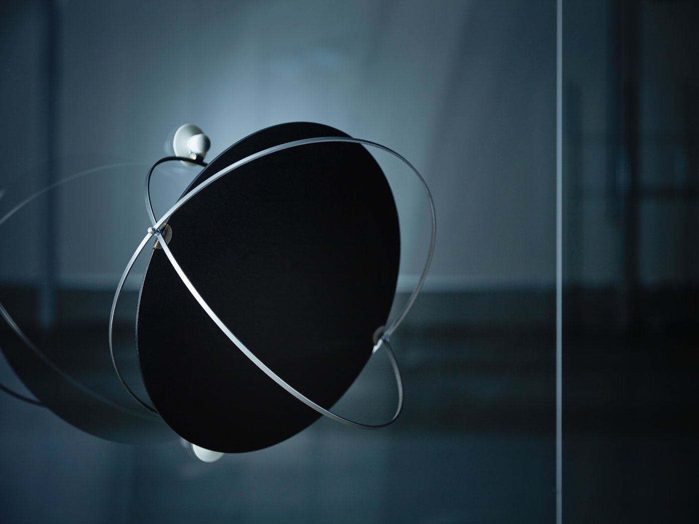 Prototype of SAMMANLÄNKAD solar-powered pendant lamp in a dimly lit space, attached to a glass screen with a white suction hook.