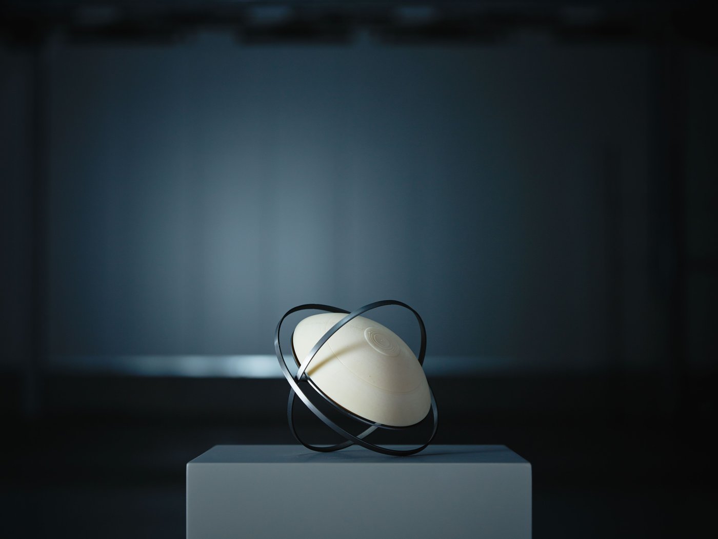 Prototype of SAMMANLÄNKAD solar-powered lamp in a dimly lit space, displayed on a plinth.