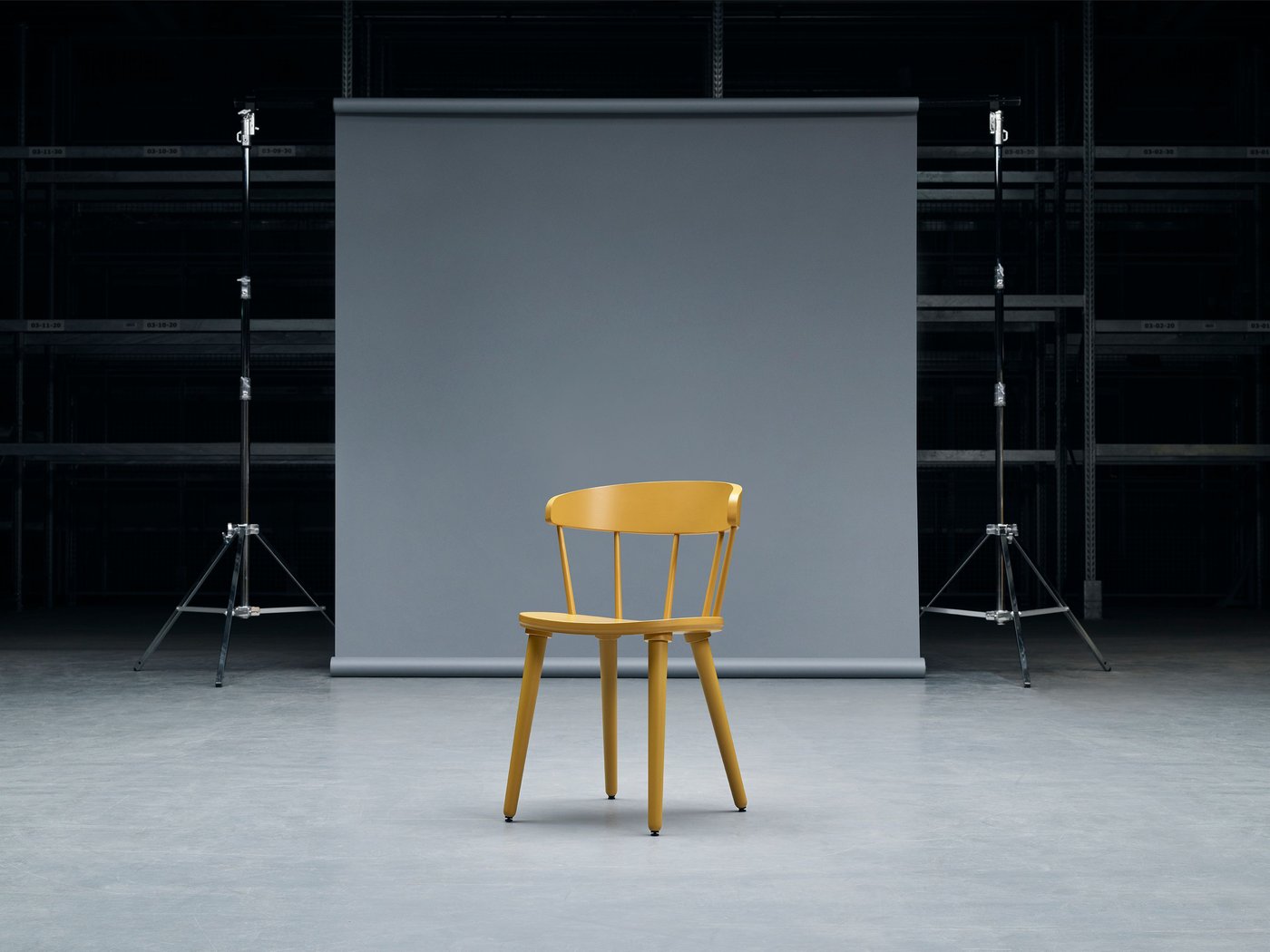 Yellow OMTÄNKSAM chair in a studio against a grey backdrop.
